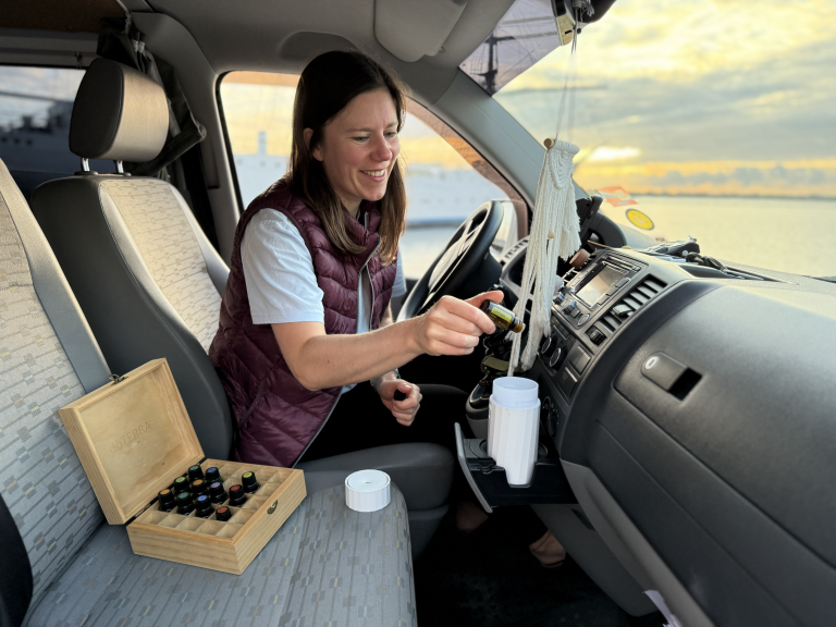 Julia im VW Bus am Steuer mit Diffuser und ätherischen Ölen neben sich